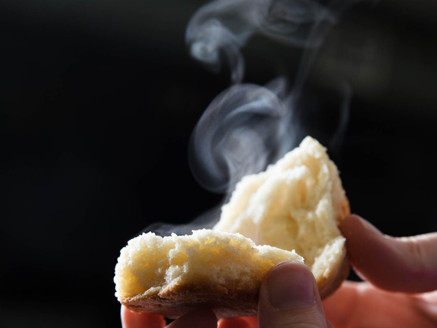 Steam escapes from a hot biscuit that's been split open.