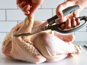 Hands using Williams Sonoma poultry shears to cut a turkey wing
