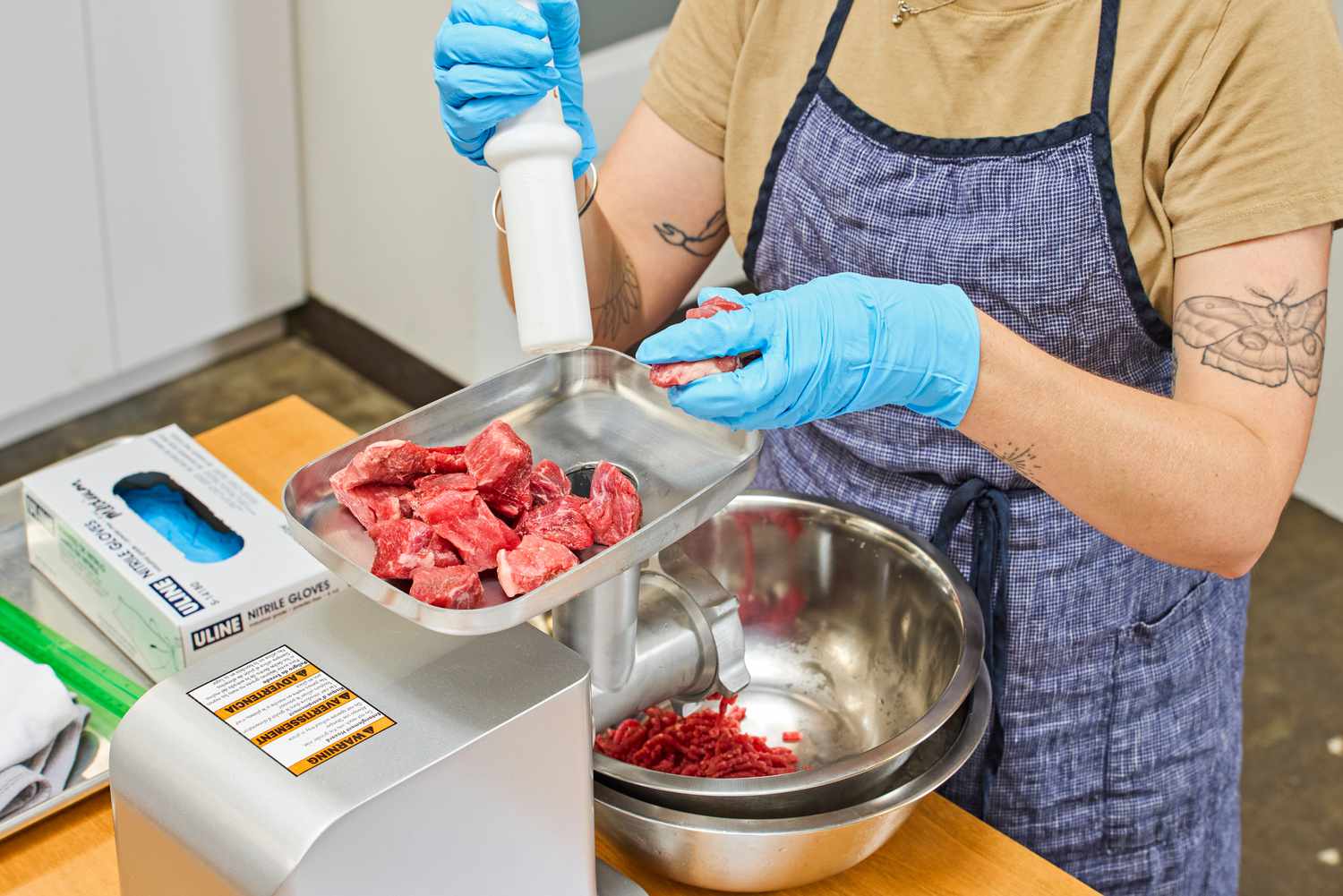 Person pushing pieces of meat from food tray of Weston #12 Electric Meat Grinder & Sausage Stuffer