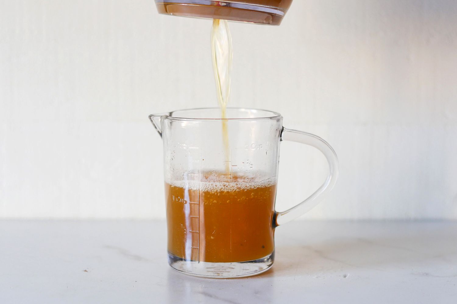 Liquid being poured into a glass measuring cup