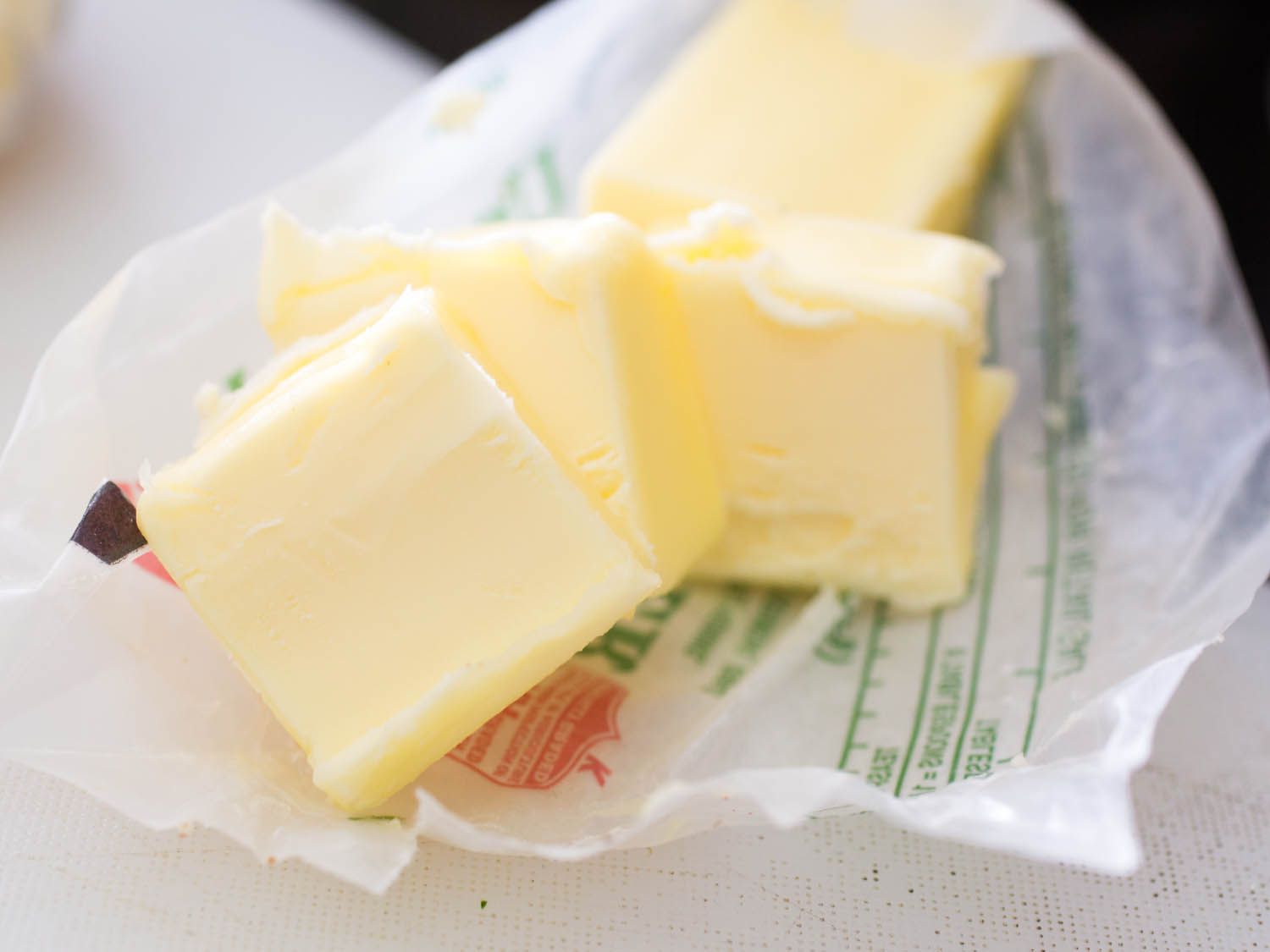A stick of butter, opened and a few tablespoons are cut from it, resting on the wrapper.