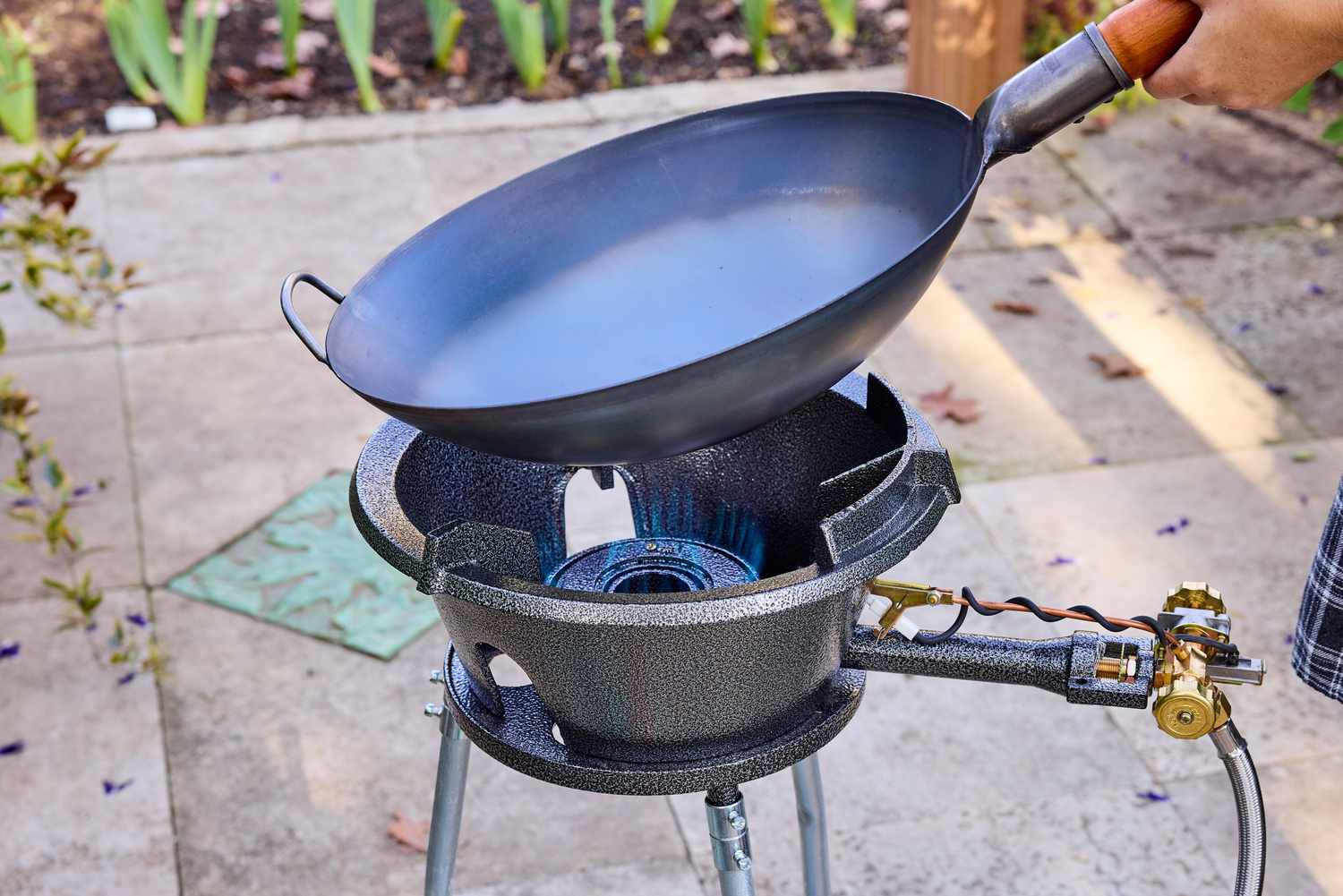 A wok being placed onto an outdoor wok burner.