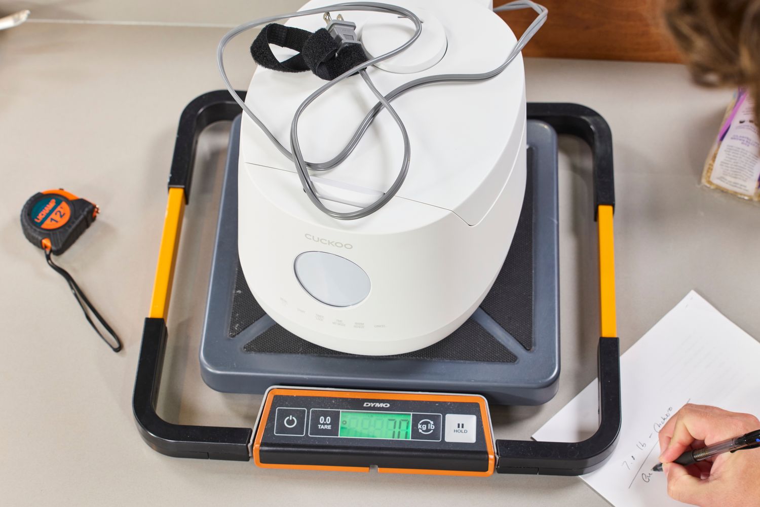 A person weighs the Cuckoo 6-Cup Micom Rice Cooker