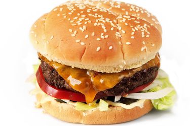 Sous vide cheeseburger on a sesame bun with tomatoes and lettuce.