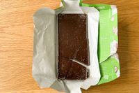 The Raaka Pink Sea Salt Dark Chocolate Bar unwrapped on a wood surface