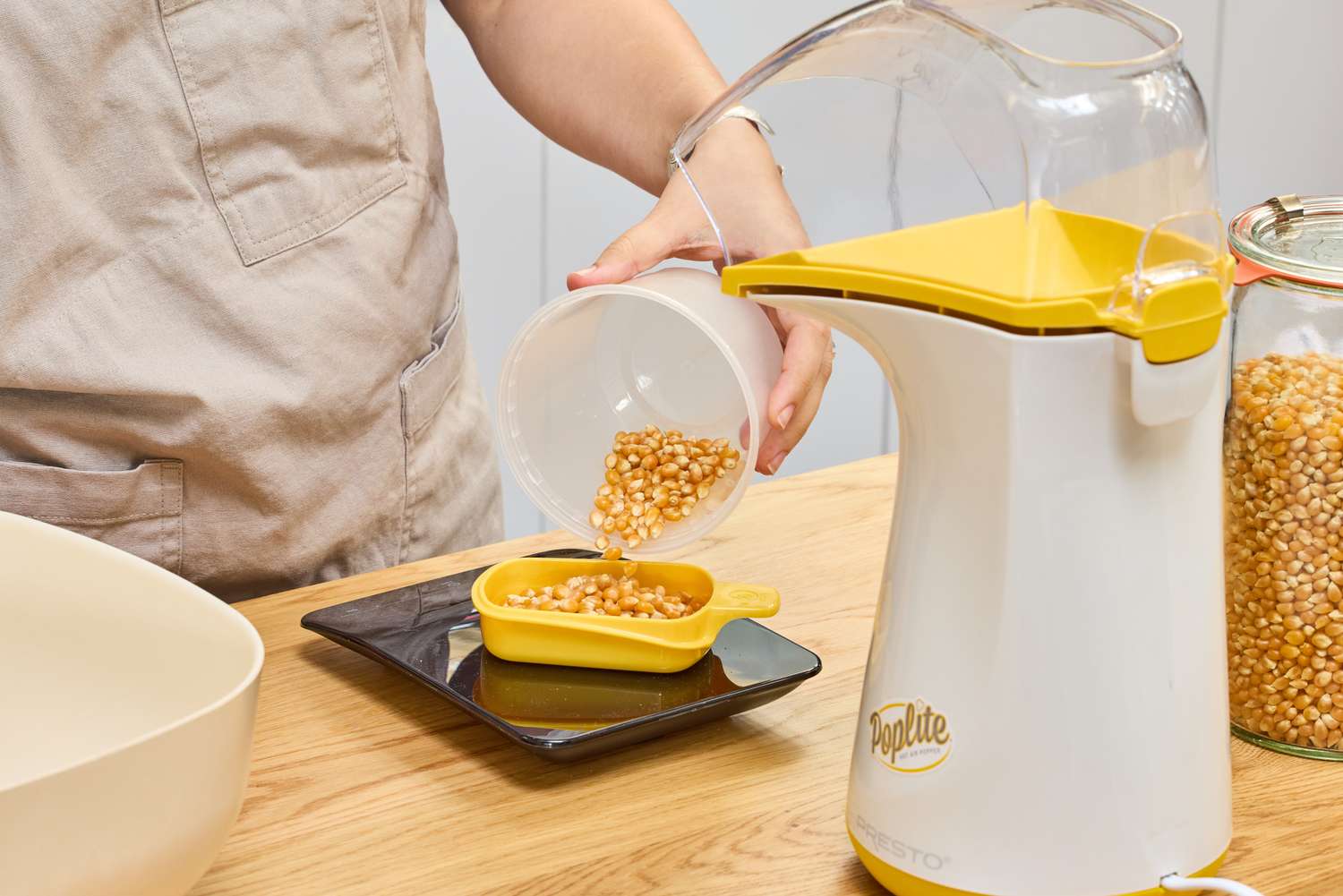 A person measures kernels before popping in the Presto Poplite Hot Air Popper