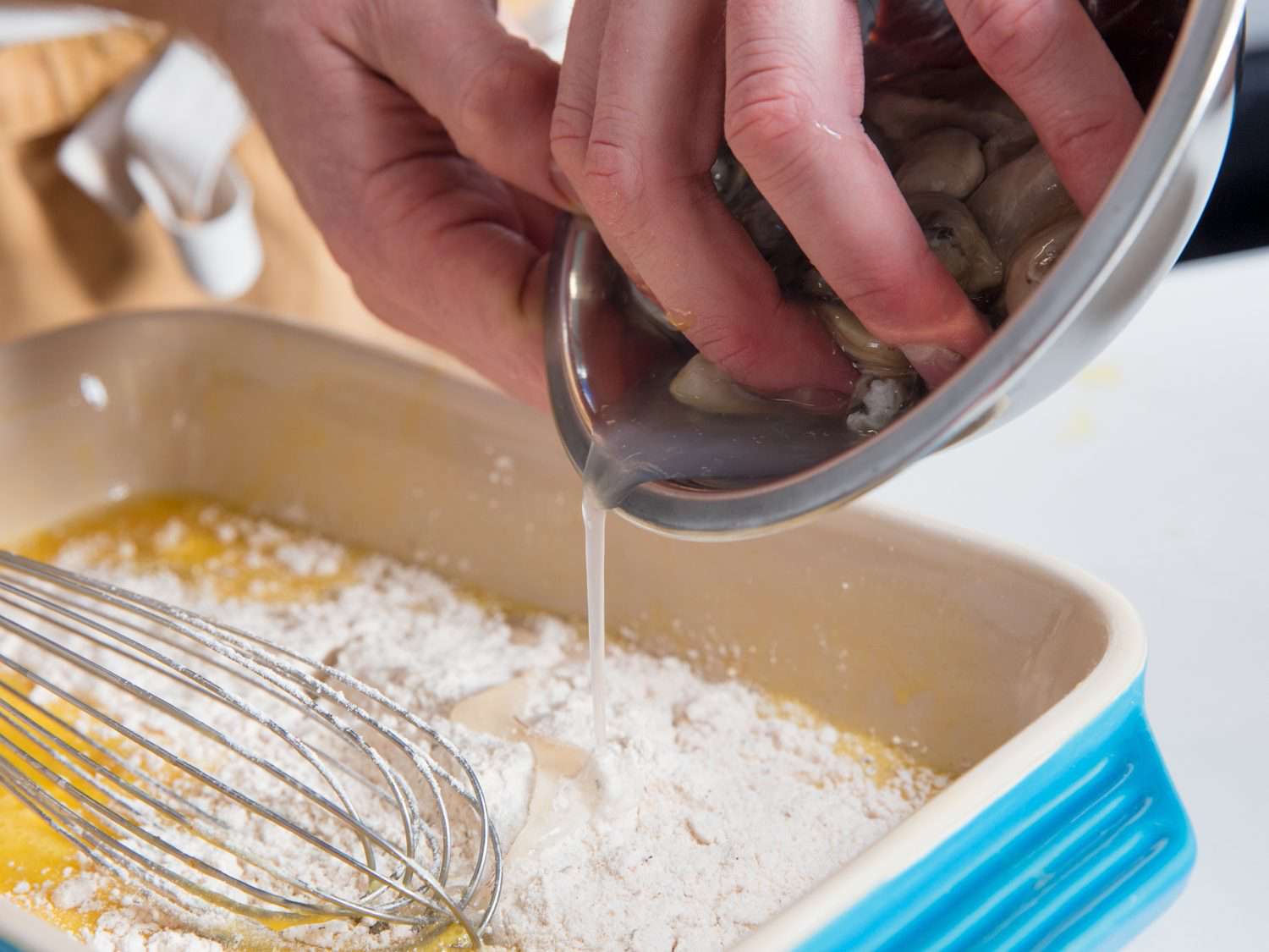 Adding oyster liquor to dredge mixture for po' boys.