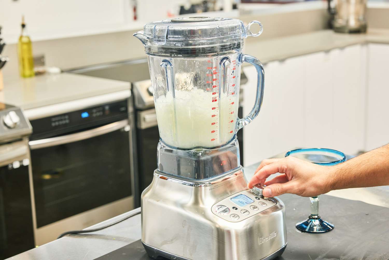 A person makes a drink in the Breville Stainless Steel Super Q Blender