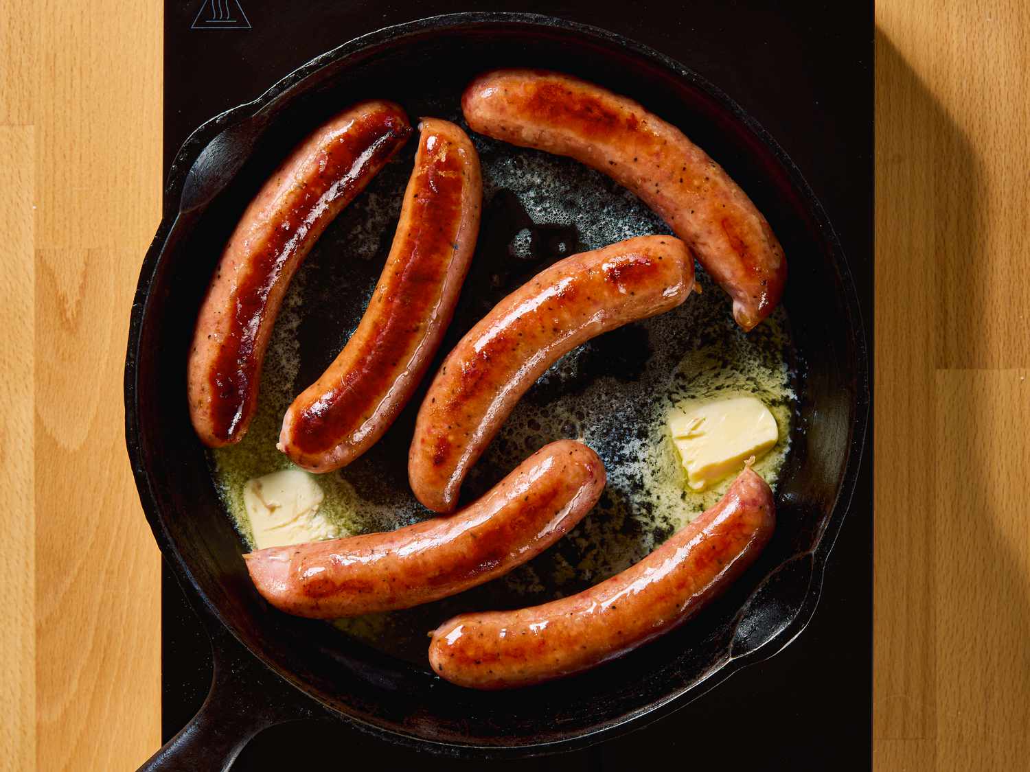 Sausages cooking in a skillet with butter