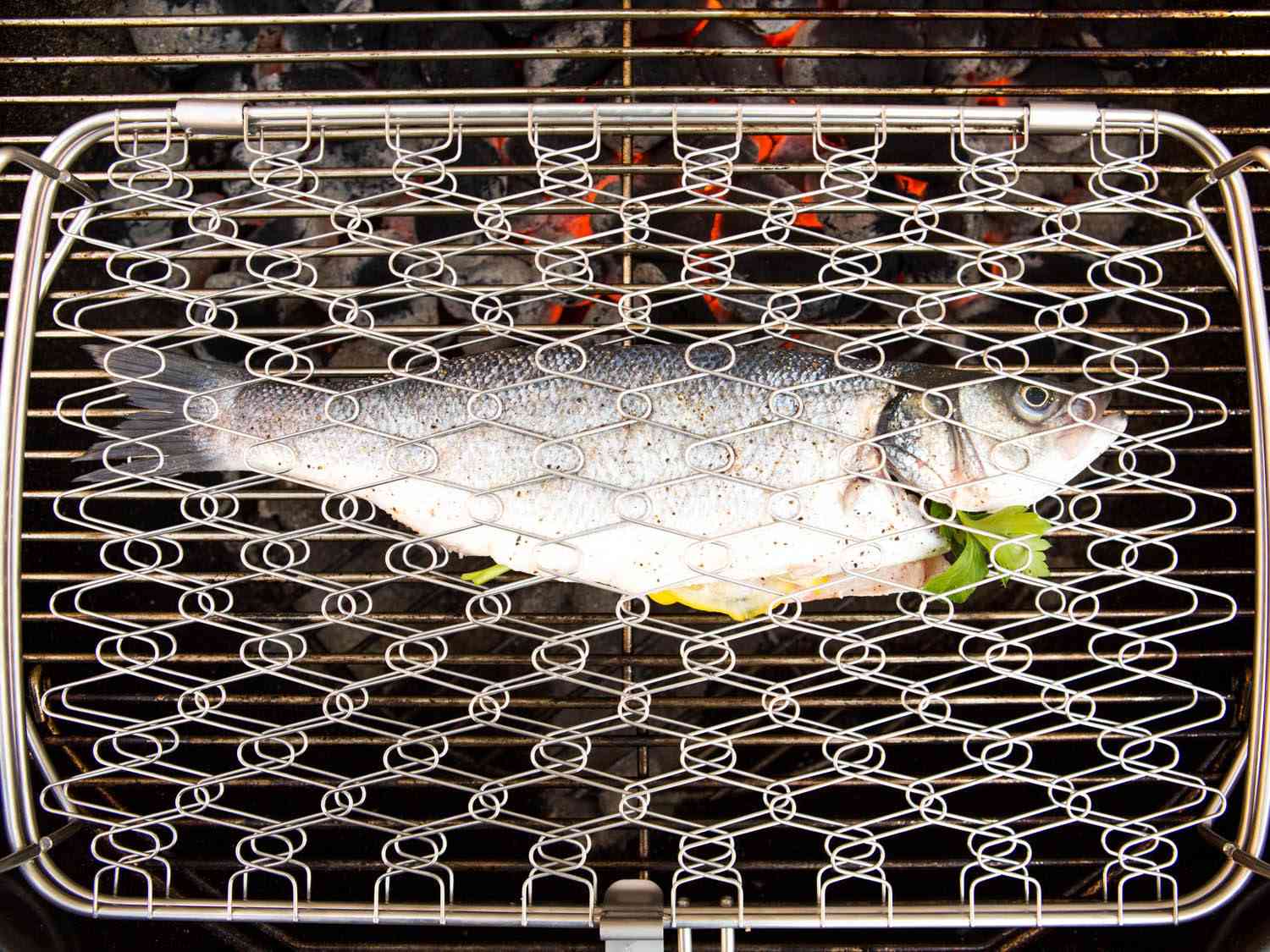 Whole fish in a traditional American-style fish basket on the grill.