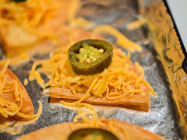 Closeup of an assembled nachos on a foil-lined baking sheet, ready to baked.