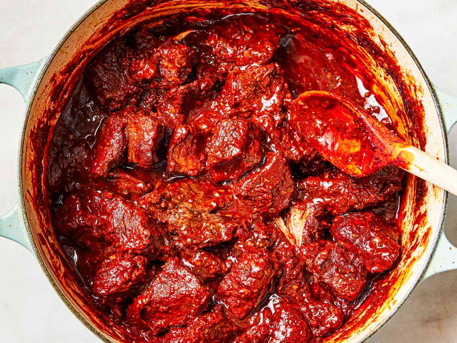 Overhead view of meat and sauce thickened in Dutch oven.