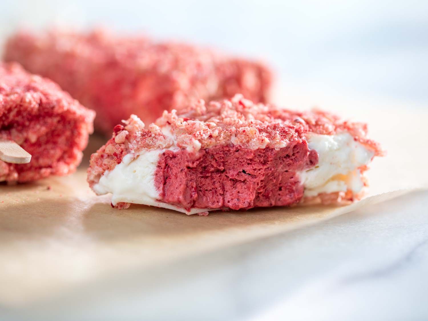 Closeup of a homemade strawberry short cake bar. The bar has been bitten to reveal the rosy interior.