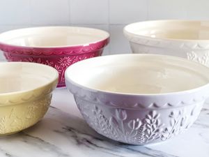 Four Mason Cash ceramic mixing bowls with floral designs arranged on a marble surface