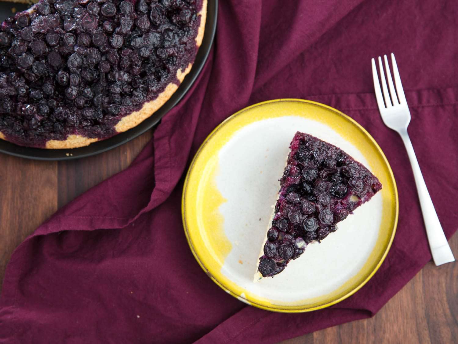 Overhead view of a sliced and plated wedge of upside-down blueberry muffin.