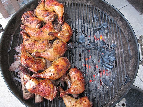 Jerk chicken steaming over moist green wood on charcoal grill