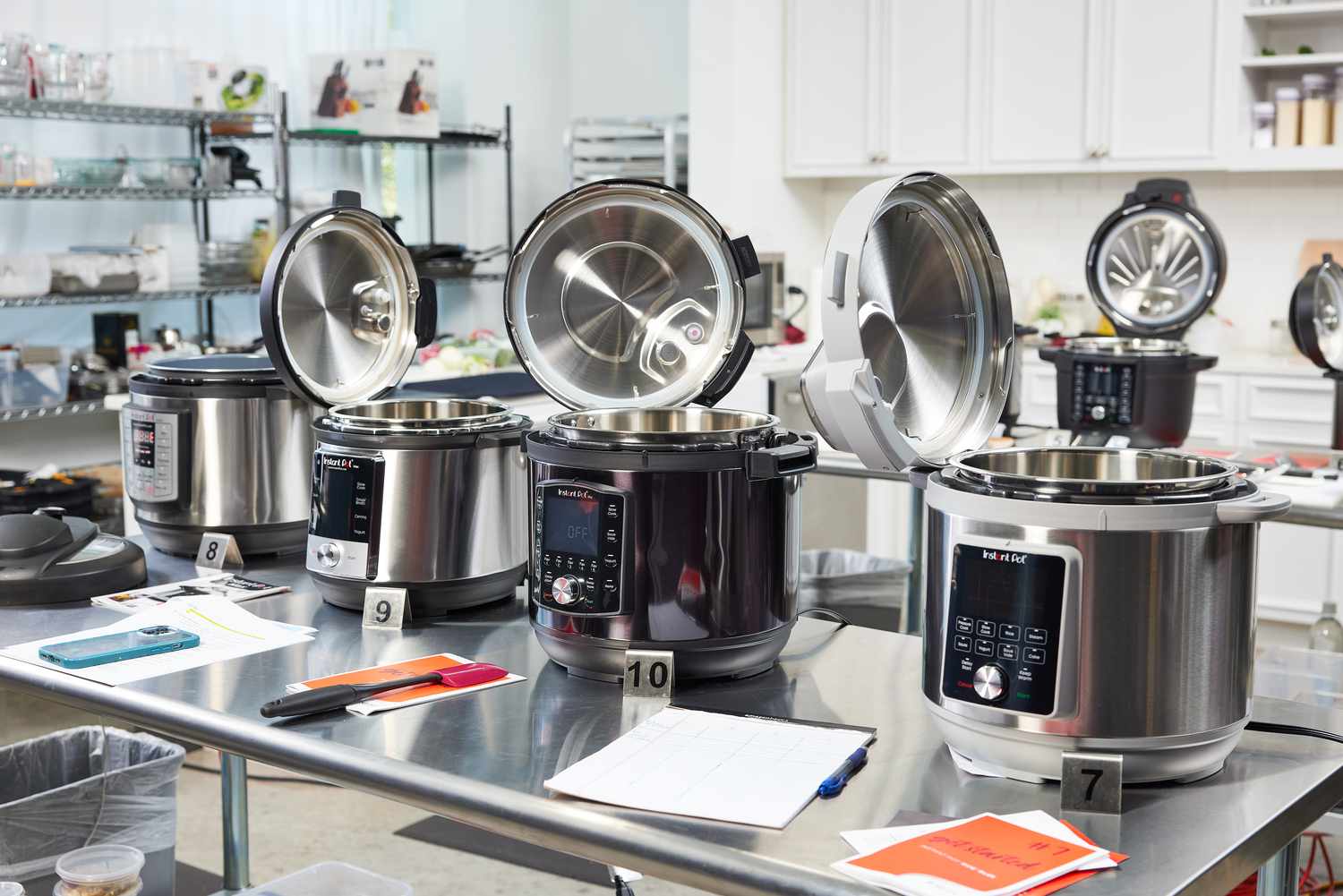 Several Instant Pots on stainless steel tables with their lids open