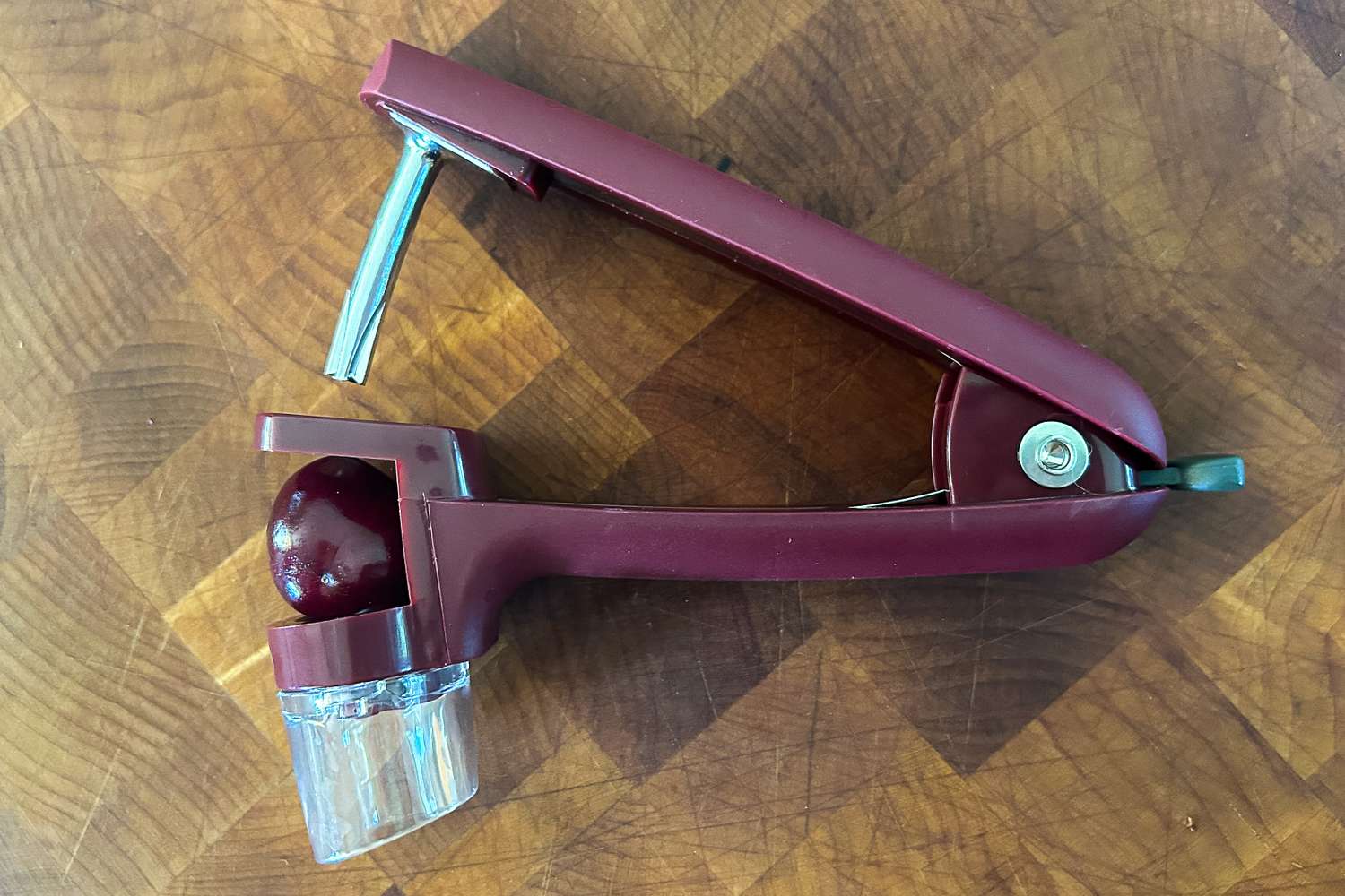 The OXO cherry pitter on a wooden cutting board