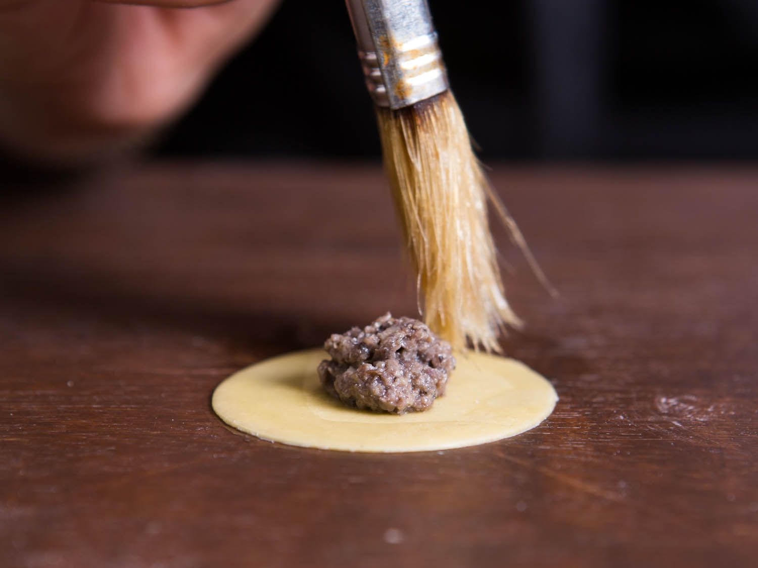 Brushing the edge of tortellini with water. 