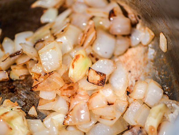 Close-up of chopped onions cooking and getting browned in a saucepan.