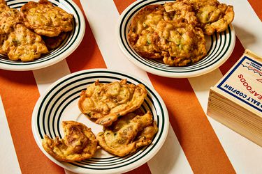 3 plates of bacalaitos and a wooden box of cod fish on red and white striped tablecloth 