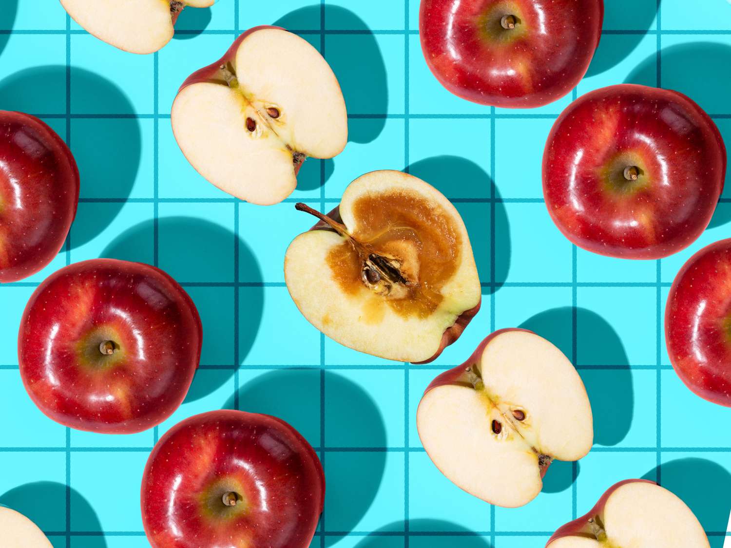 Red apples arranged on a blue grid background some cut in half to reveal their interiors