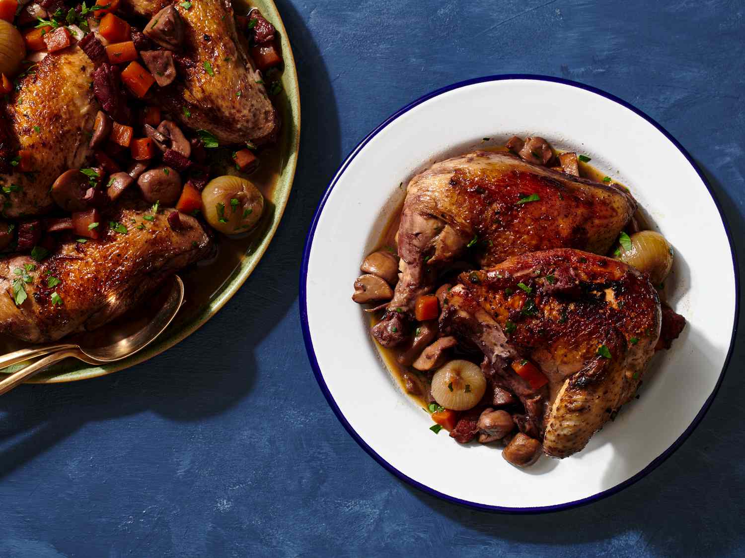 A serving of Coq au Vin, sprinkled with parsley, on a white, blue-rimmed plate.