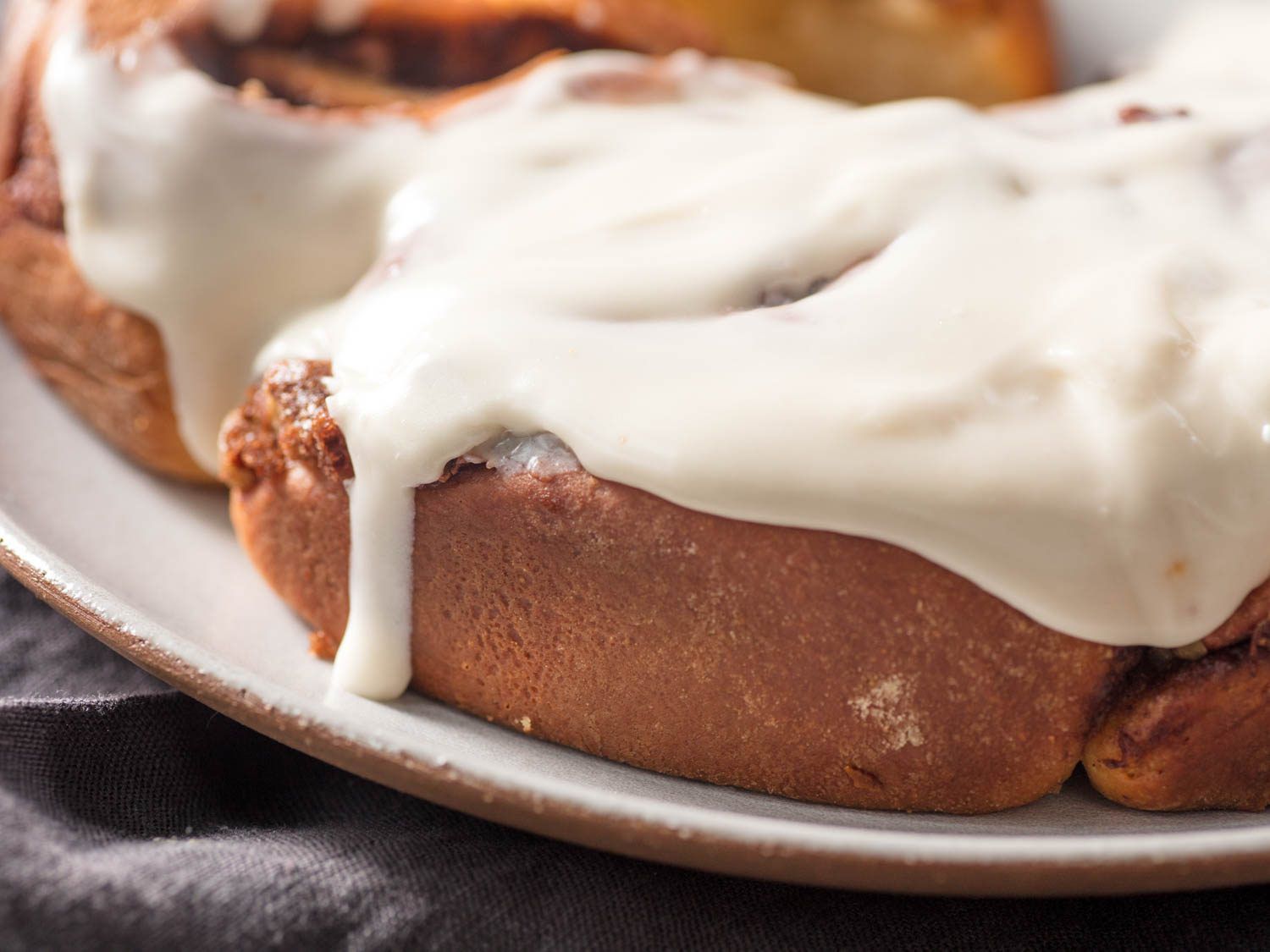 Close-up of gooey powdered sugar glaze–topped cinnamon rolls.