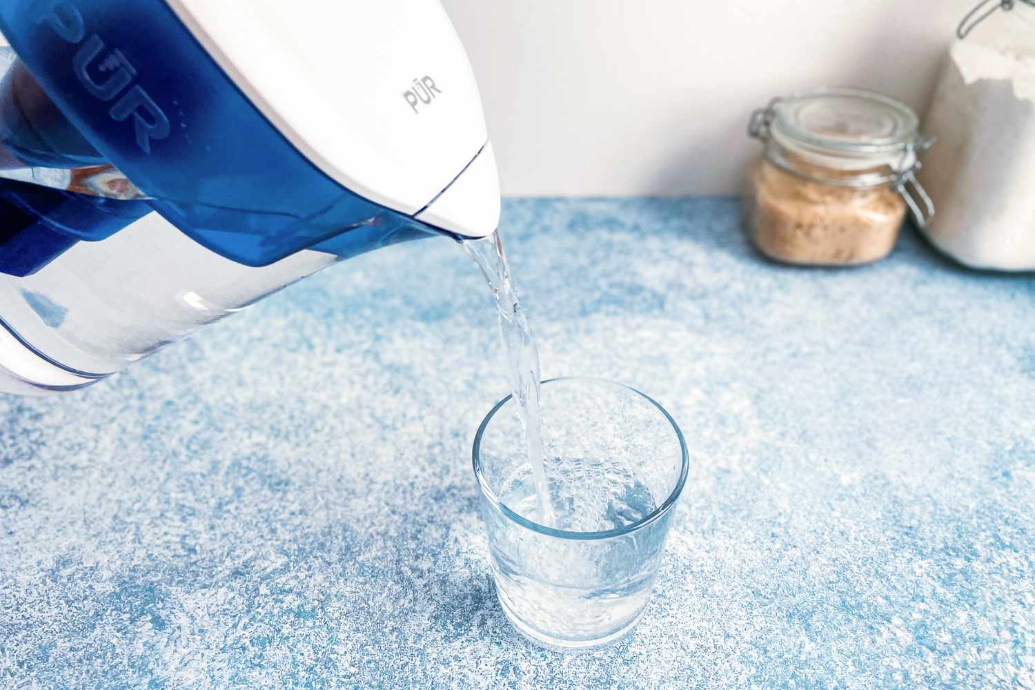 a water filter pitcher pouring water into a glass