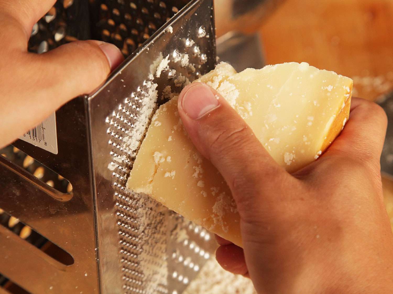 Grating Parmigiano Reggiano on a box grater.