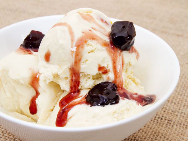 Scoops of Bourbon and Orange Ice Cream topped with dark maraschino cherries in a white bowl