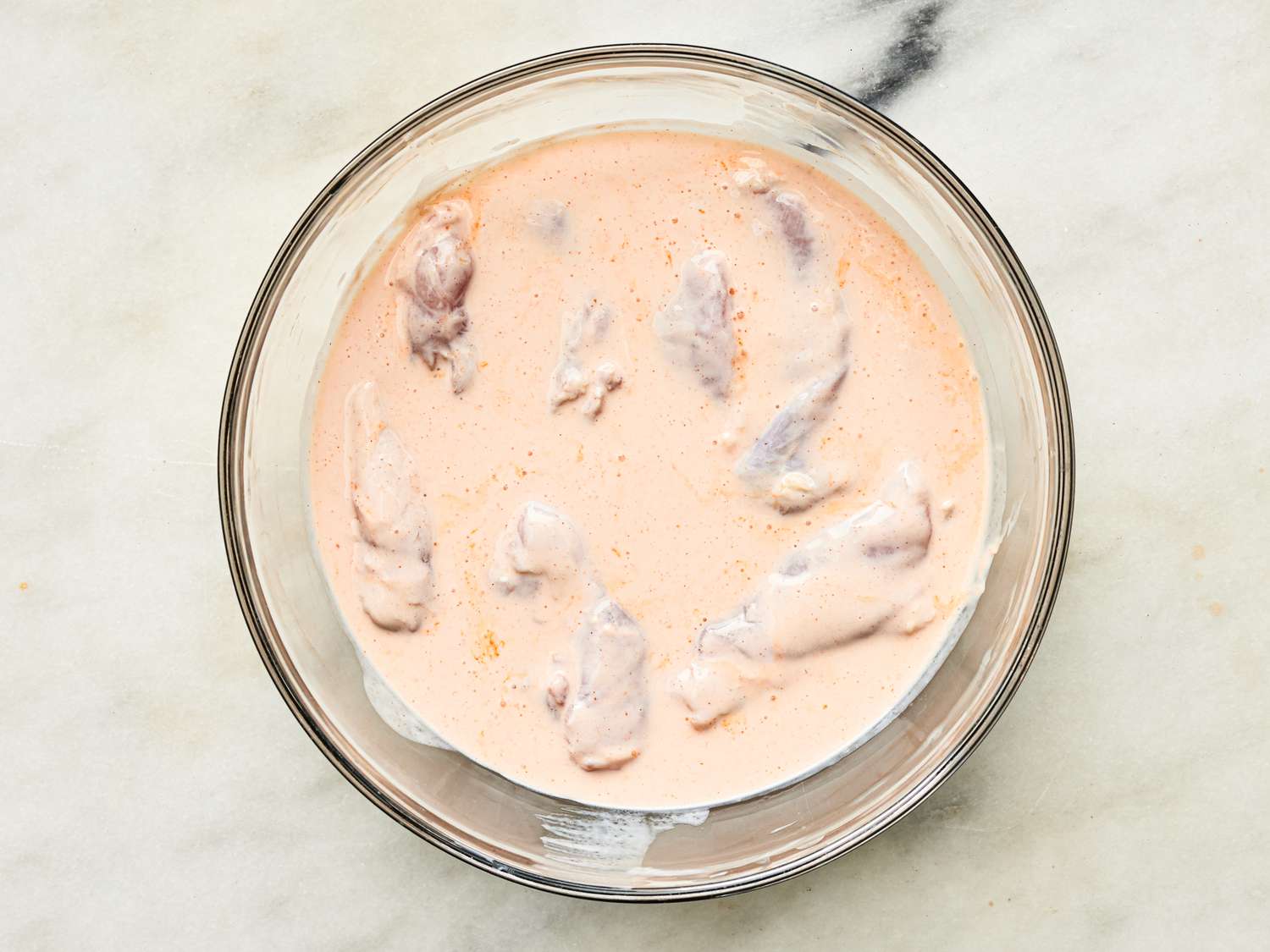 Overhead view of chicken in buttermilk mixture
