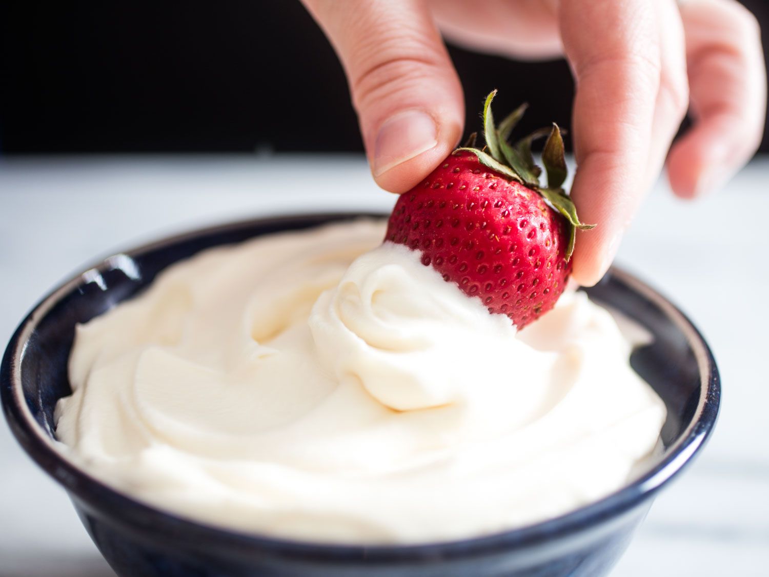 Dipping a strawberry into a bowl of homemade Cool Whip. 