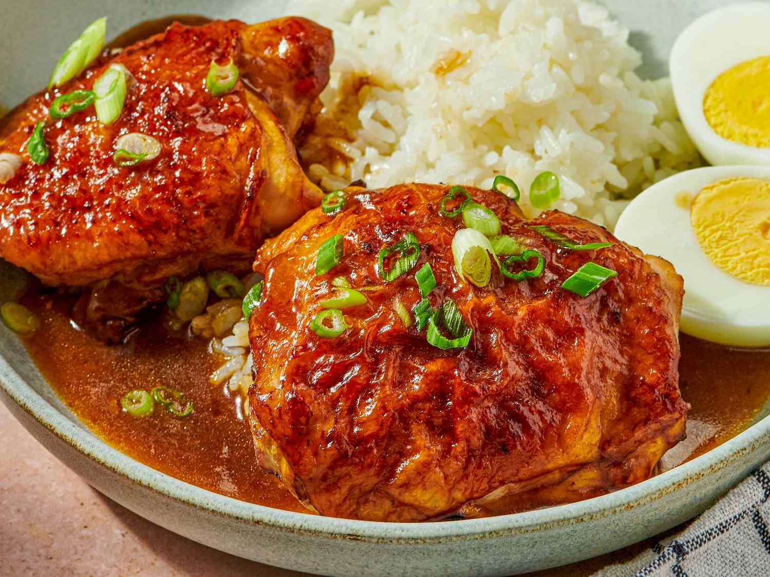 Soy and sesame roast chicken served with rice and boiled eggs garnished with scallions