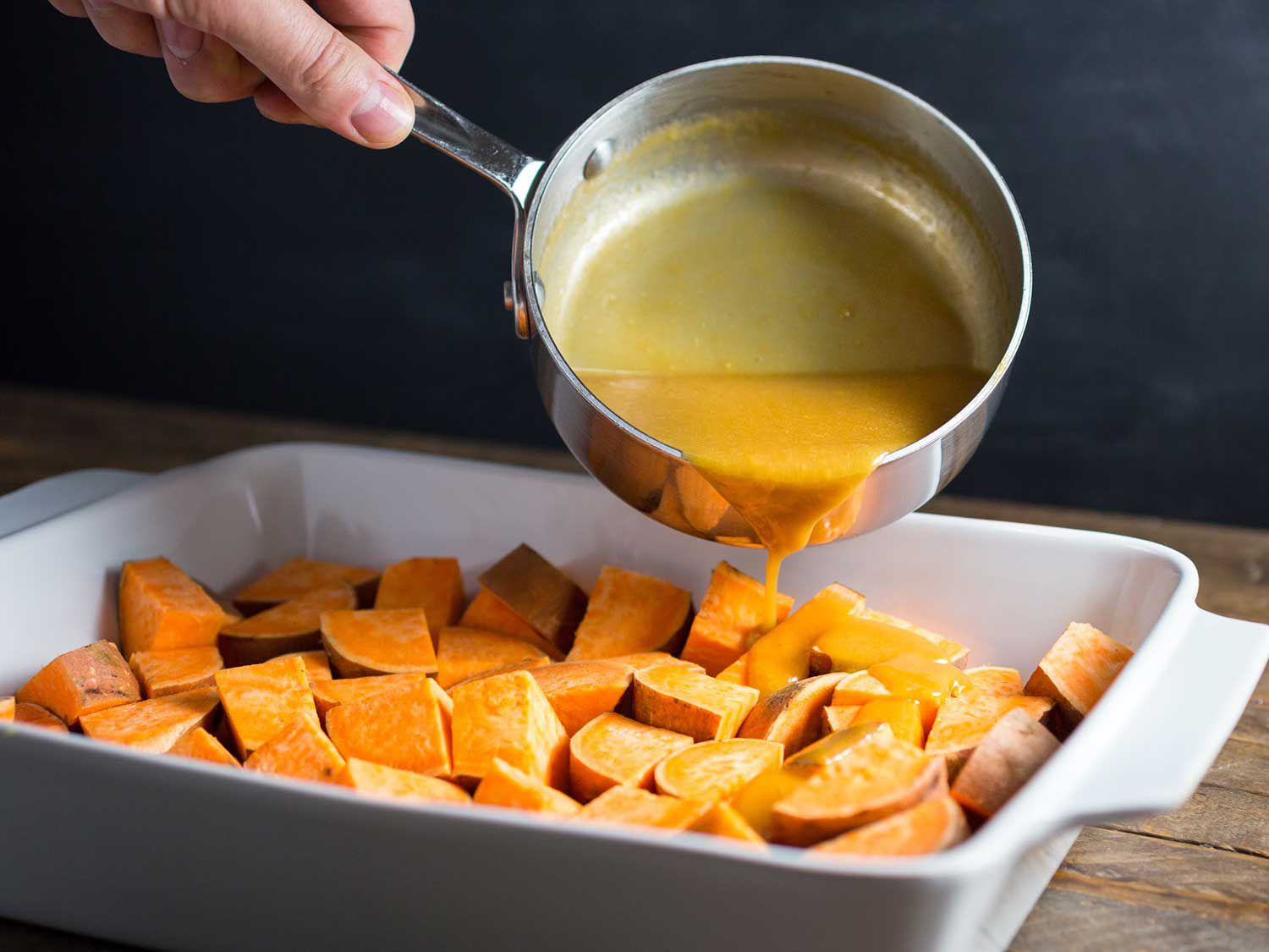The miso butter mixture is poured over chunks of sweet potato in a baking dish.