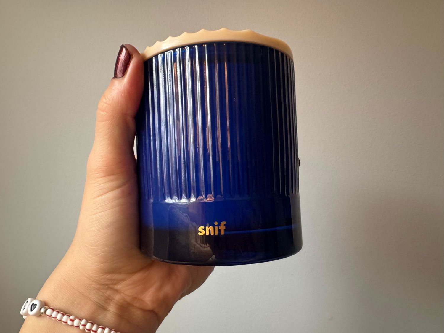 Hand holding a blue Snif candle with a ribbed design