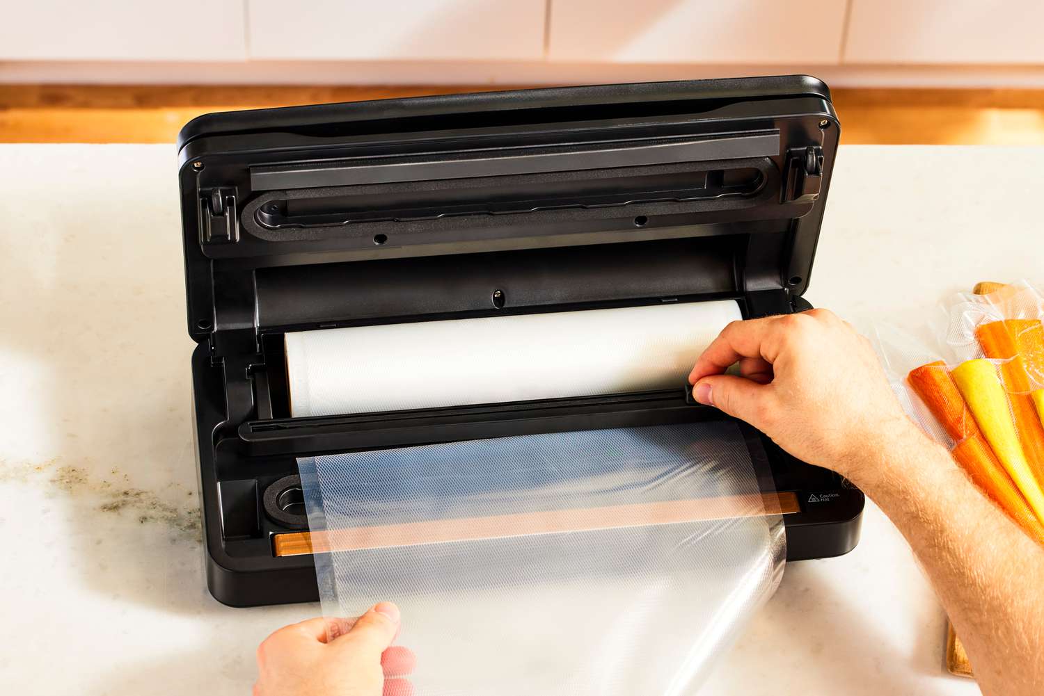 A person using the Anova Precision Pro vacuum sealer's built-in bag cutter to trim a bag off of a roll.