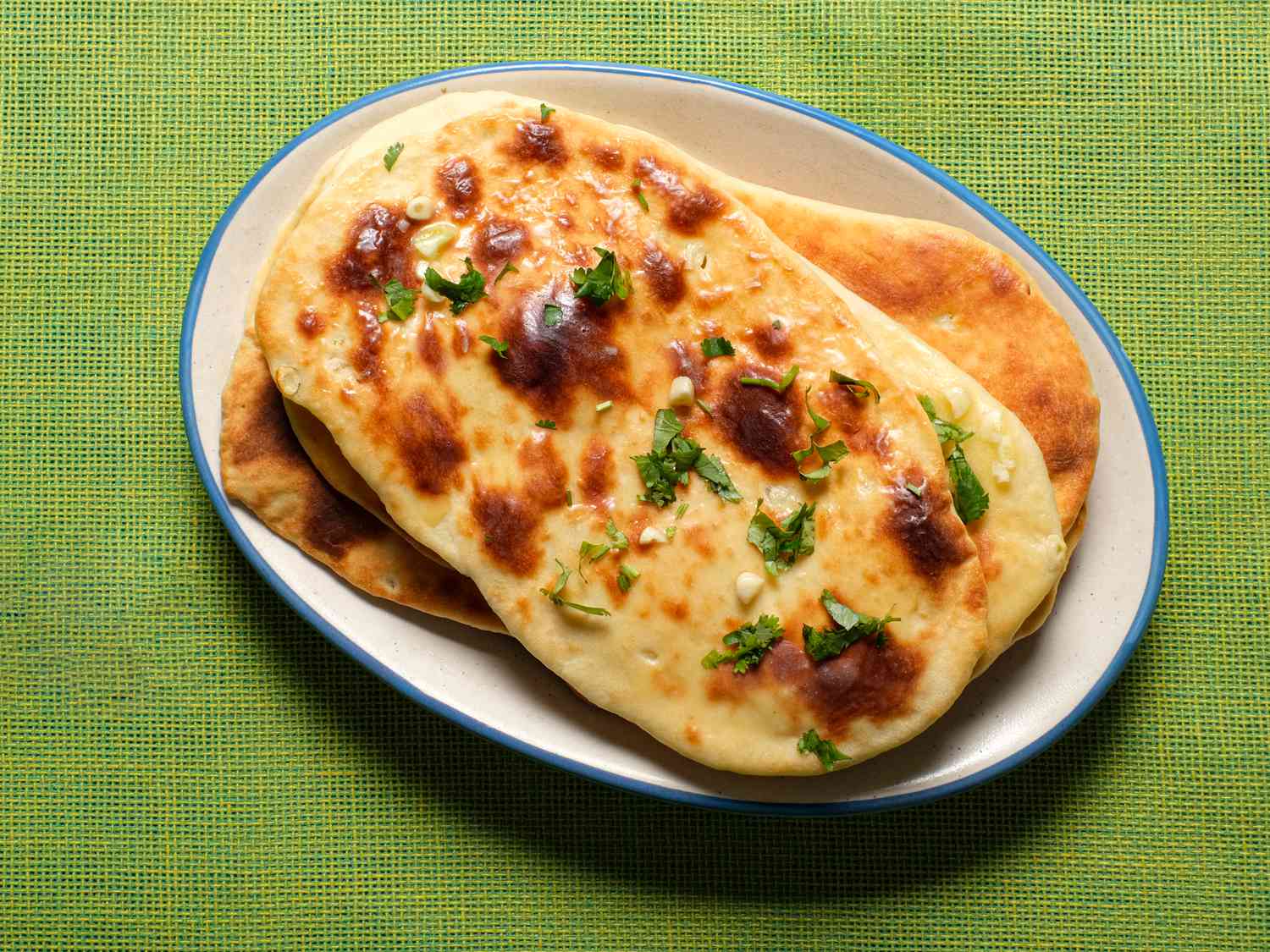 Garlic Naan on a white plate on a lime green tablecloth