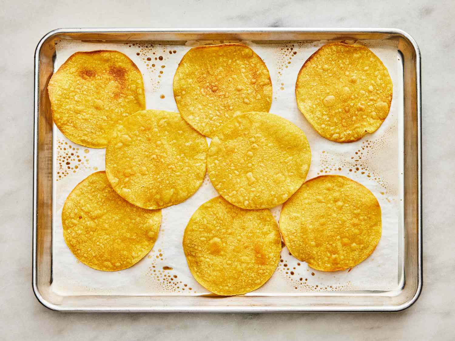 Baked tortillas on a sheet pan, slightly browned 