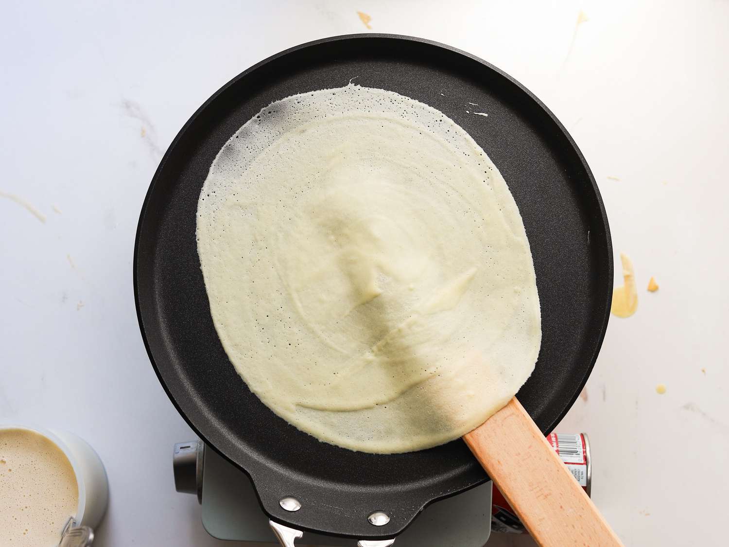 A spatula being used to flip a crepe.