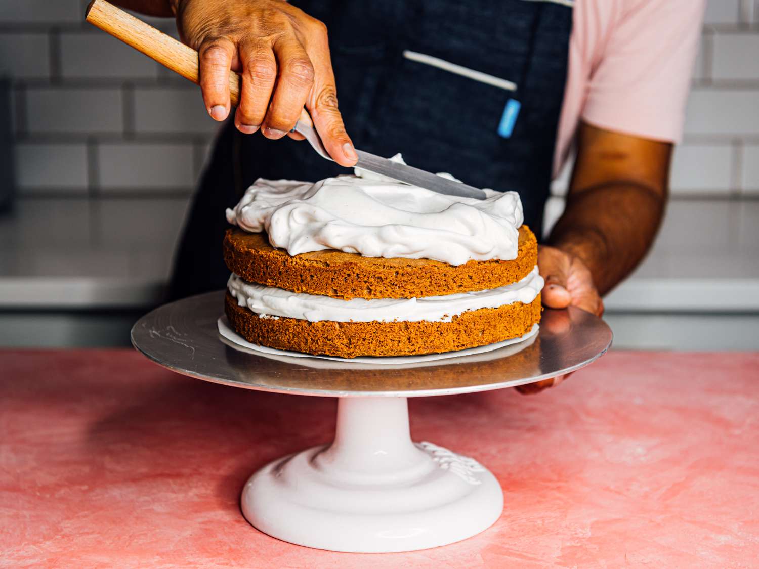 a man frosting a cake with aquafaba meringue frosting