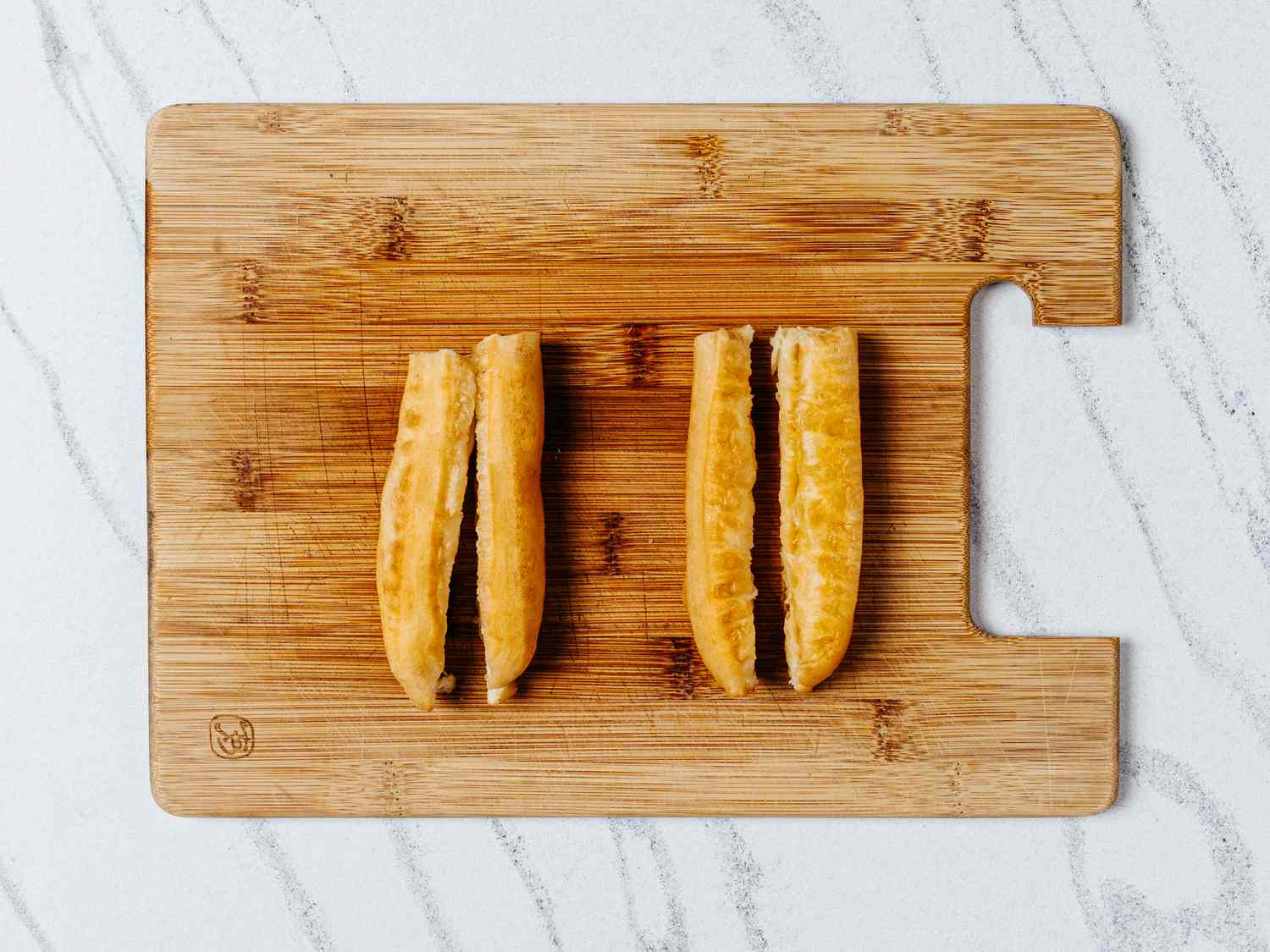 Crullers sliced in half lengthwise on a wooden cutting board 