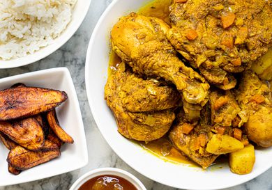 Overhead view of curry chicken with rice and fried plantains