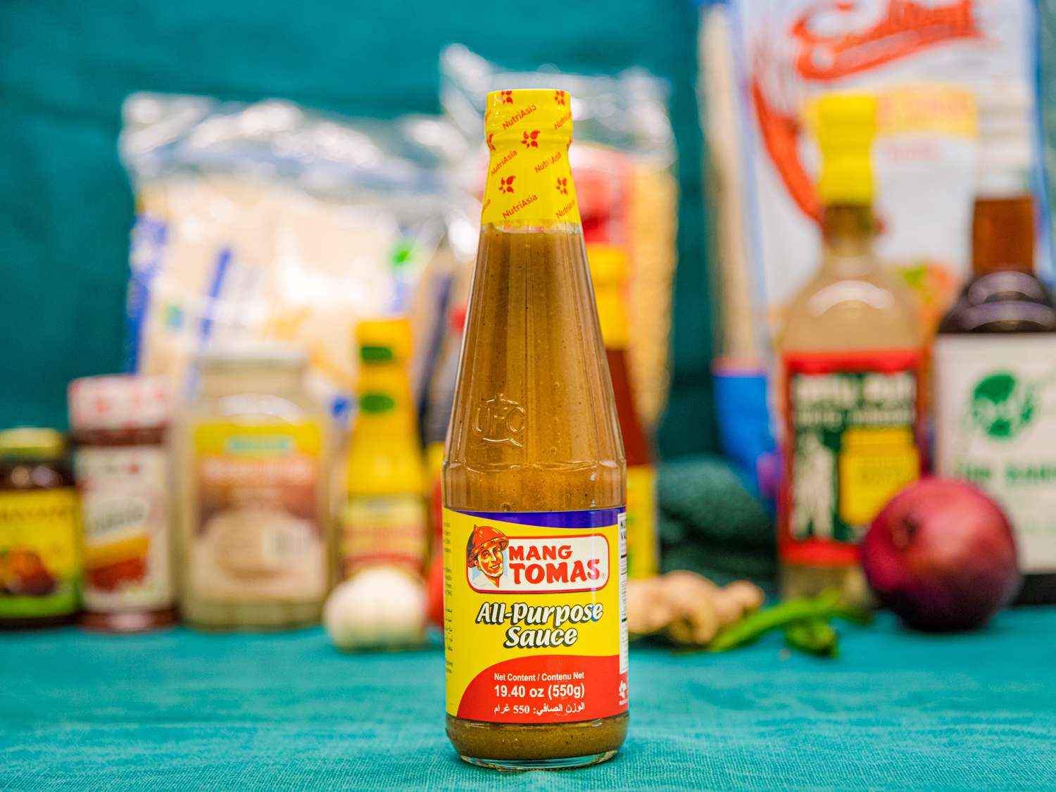 A bottle of Mang Tomas All-Purpose Sauce on a blue backdrop