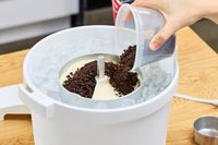 A person adding toppings to the Hamilton Beach Automatic Ice Cream Maker