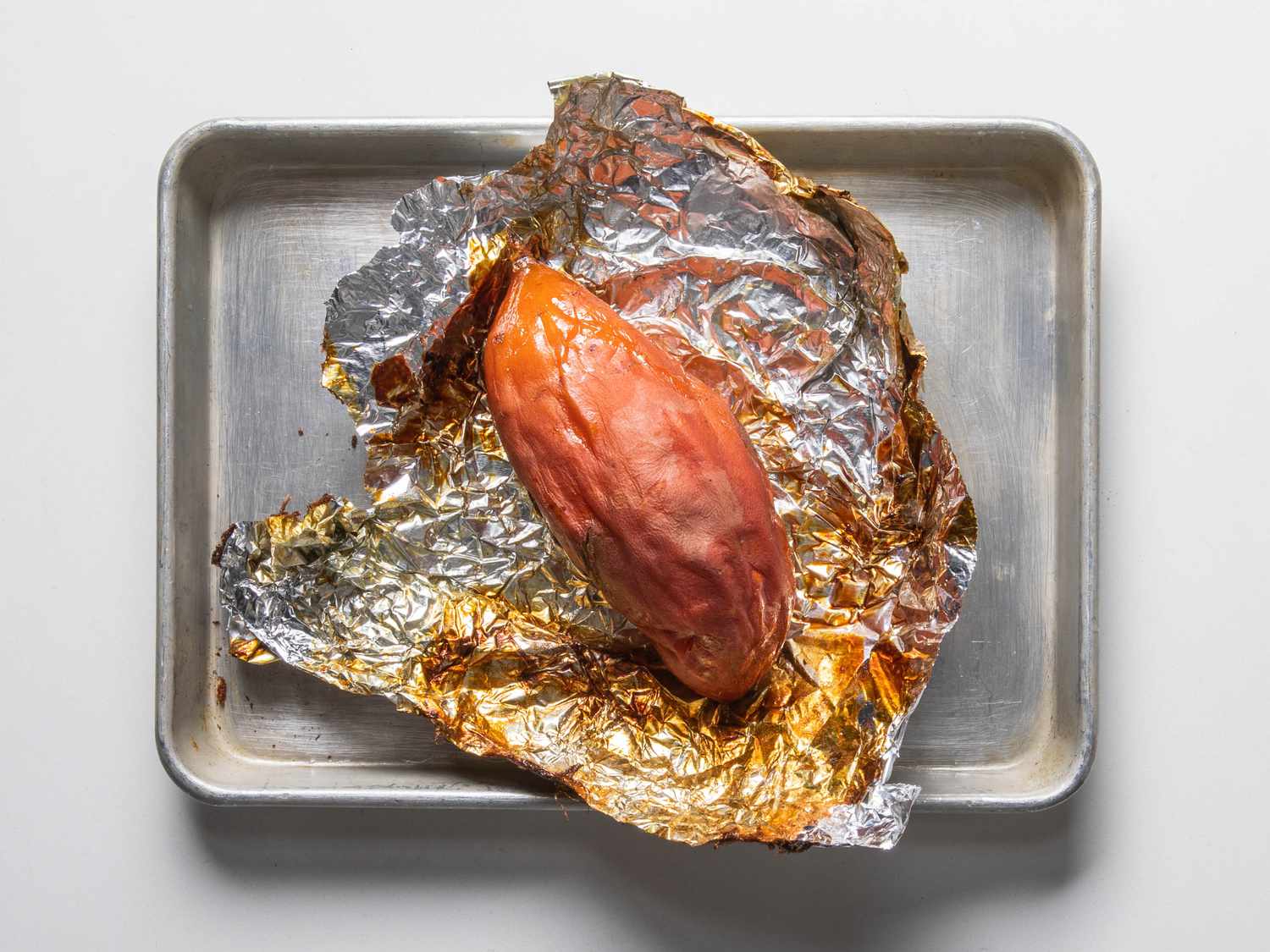 Frozen roasted sweet potato on foil in a rimmed baking sheet