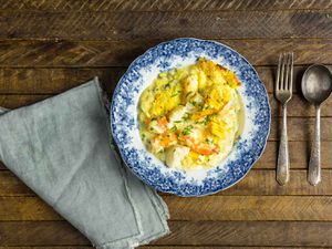  Overhead view of British Fish Pie With Smoked Salmon, Shrimp, and Mashed Potatoes, served on an antique porcelain plate.