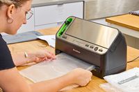 A person pulls a plastic bag from the FoodSaver V4400 2-in-1 Vacuum Sealer Machine