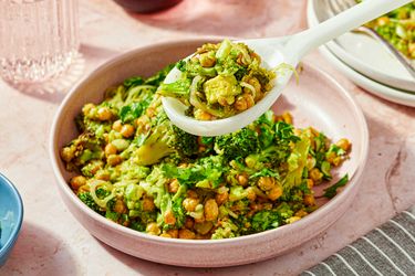 A bowl of broccoli and chickpea salad with a spoon serving a portion