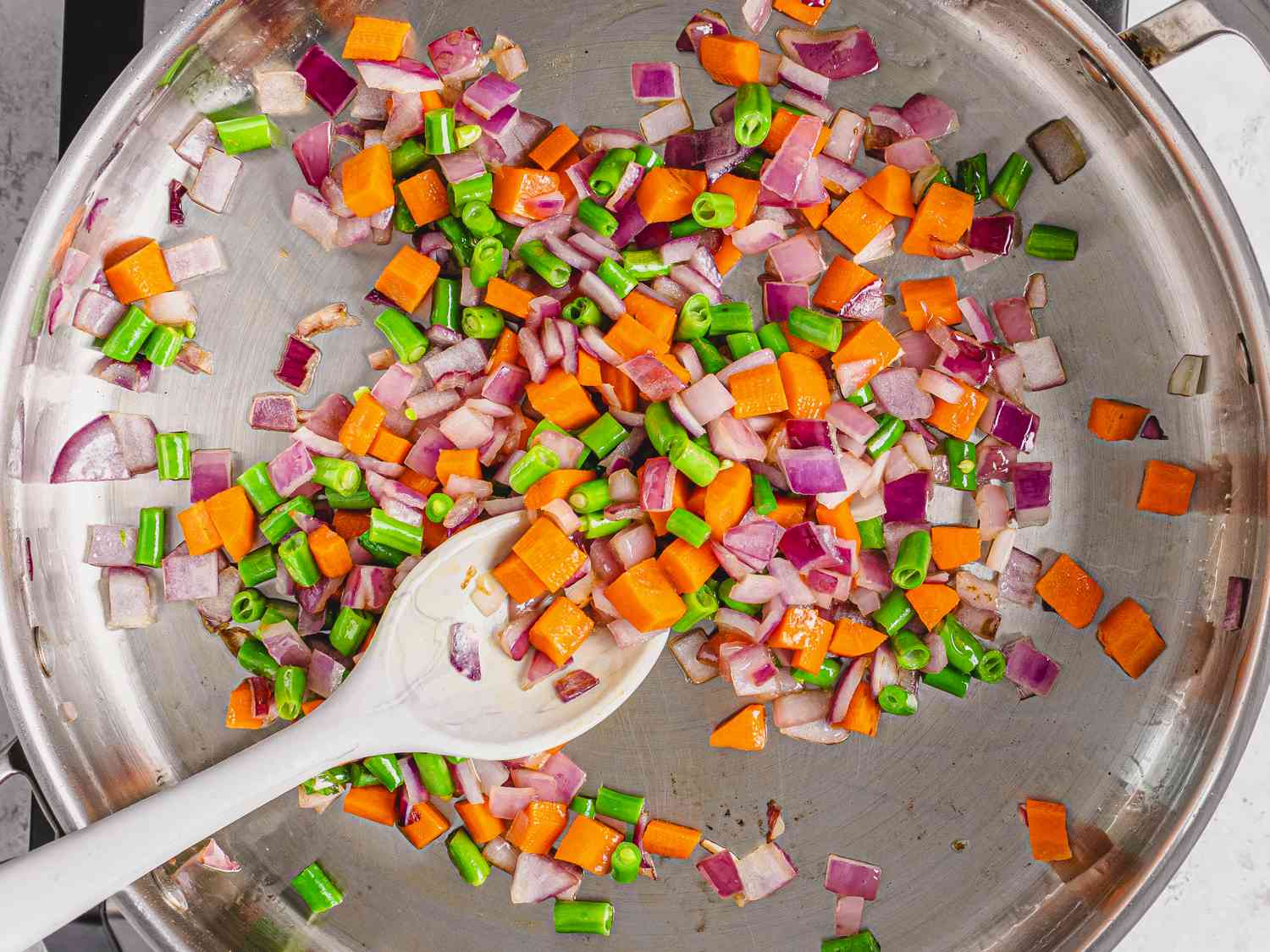 Onions, carrots and green in a saute pan with oil